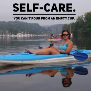 Author Lori Ann King in blue kayak, floating on the Rondout River off the Hudson River, NY. Text overlay reads: Self-care. You can't pour from an emty cup.